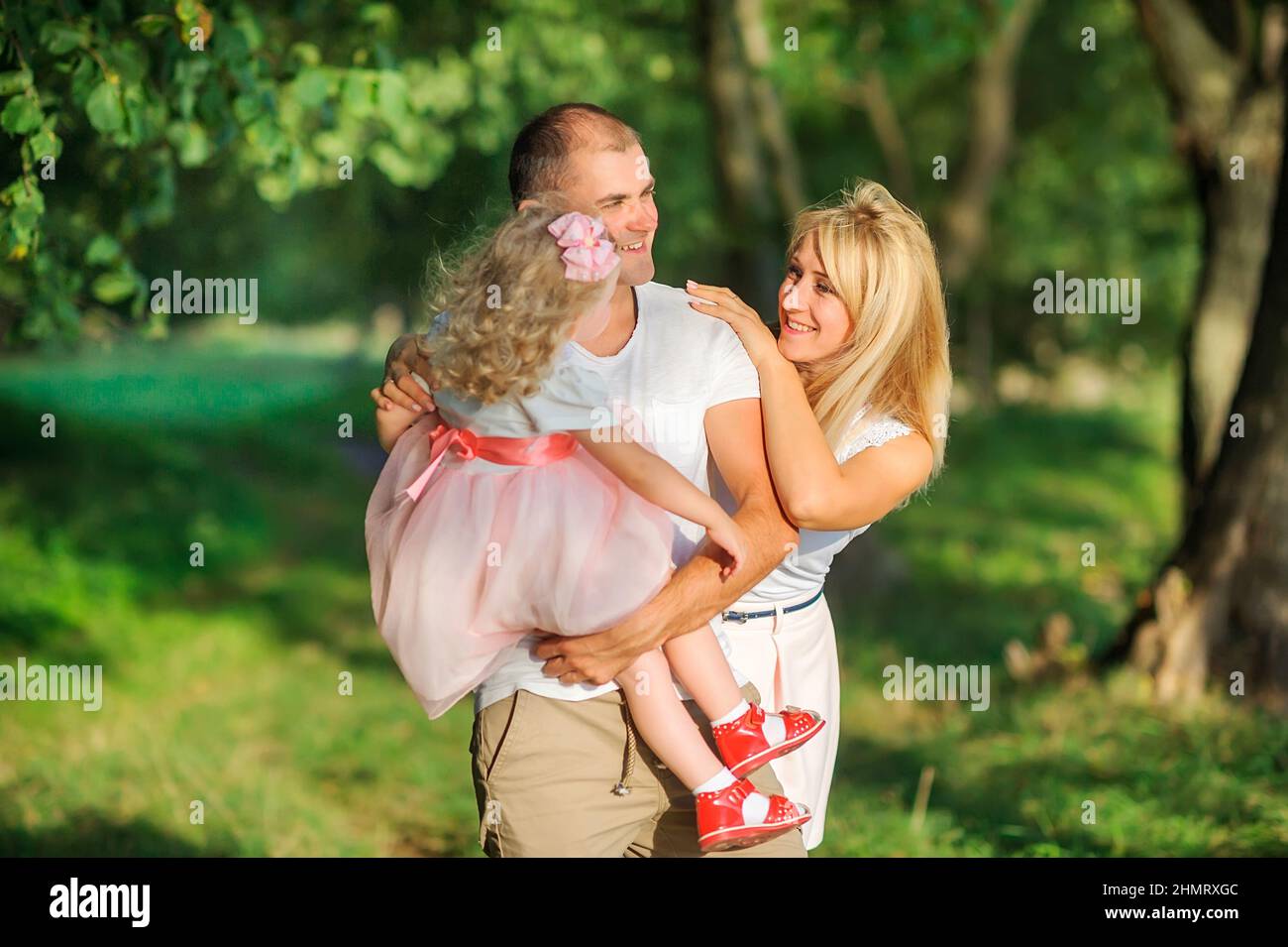 Happy family in a beautiful spring park, dad holds a daughter in his arms, having fun and smiling, healthy outdoor recreation Stock Photo