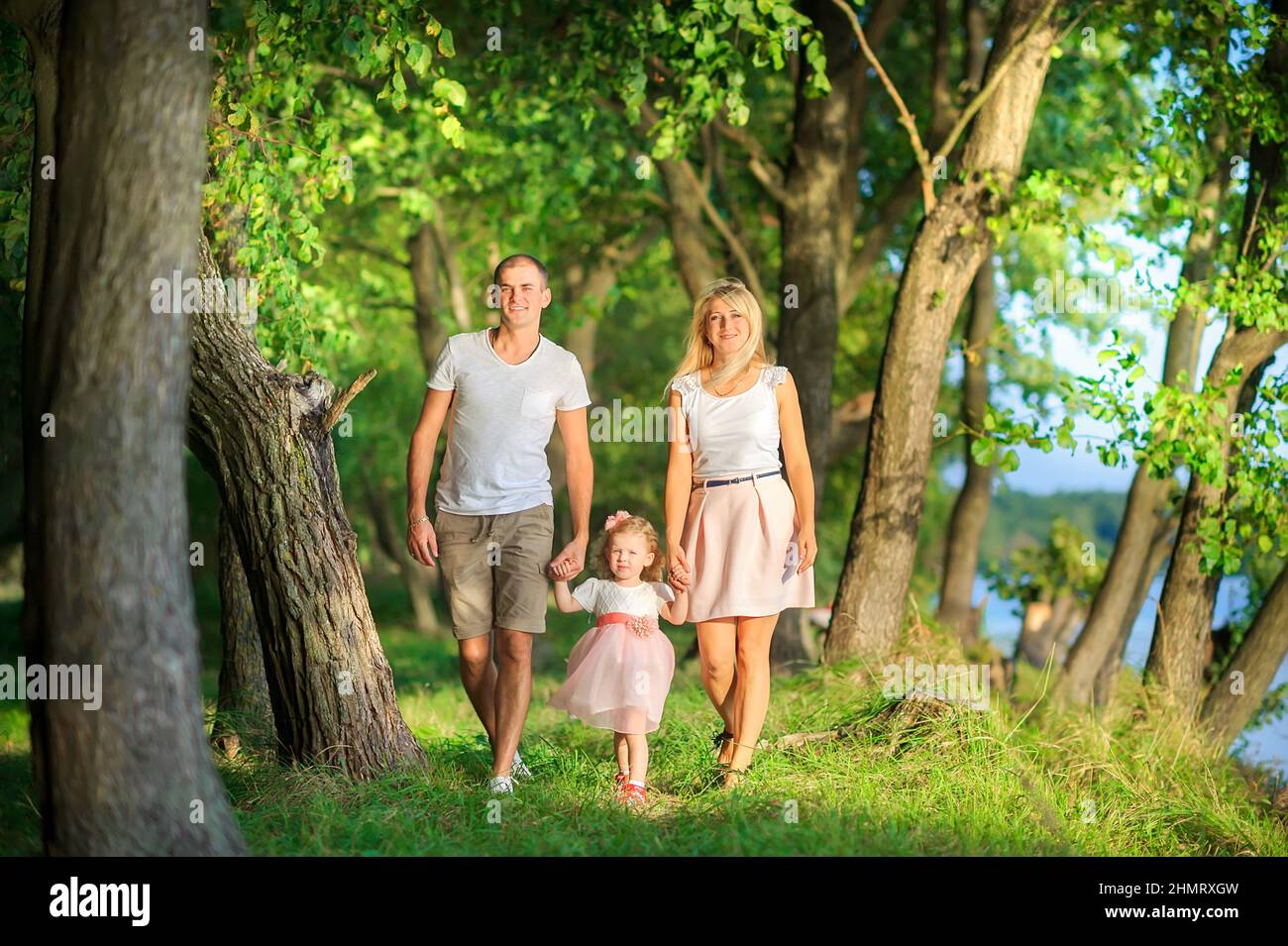Happy family walks in a beautiful spring park, holding hands and smiling, healthy outdoor recreation Stock Photo