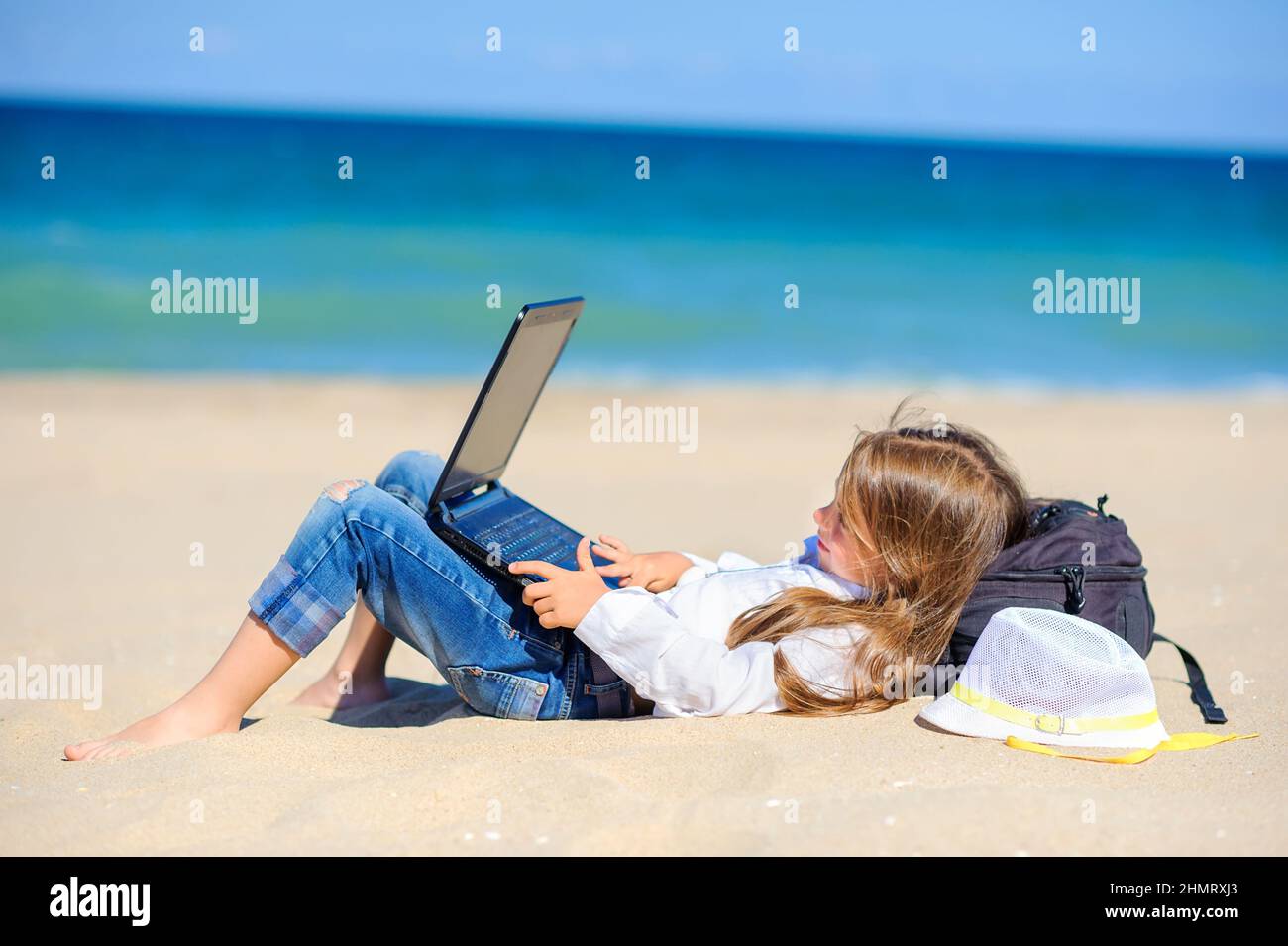 work in travel, girl teenager lies on the beach with a laptop Stock Photo