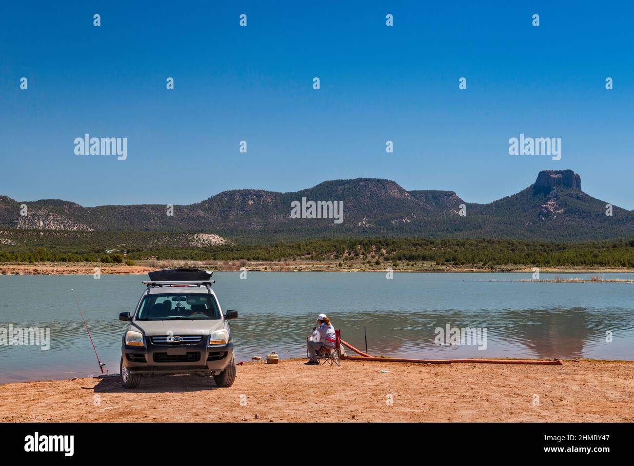 Woman angler at Tsaile Lake, Tsaile Butte on right in dist, Chuska Mountains, Canyon de Chelly Natl Monument, near Tsaile, Navajo Nation, Arizona, USA Stock Photo