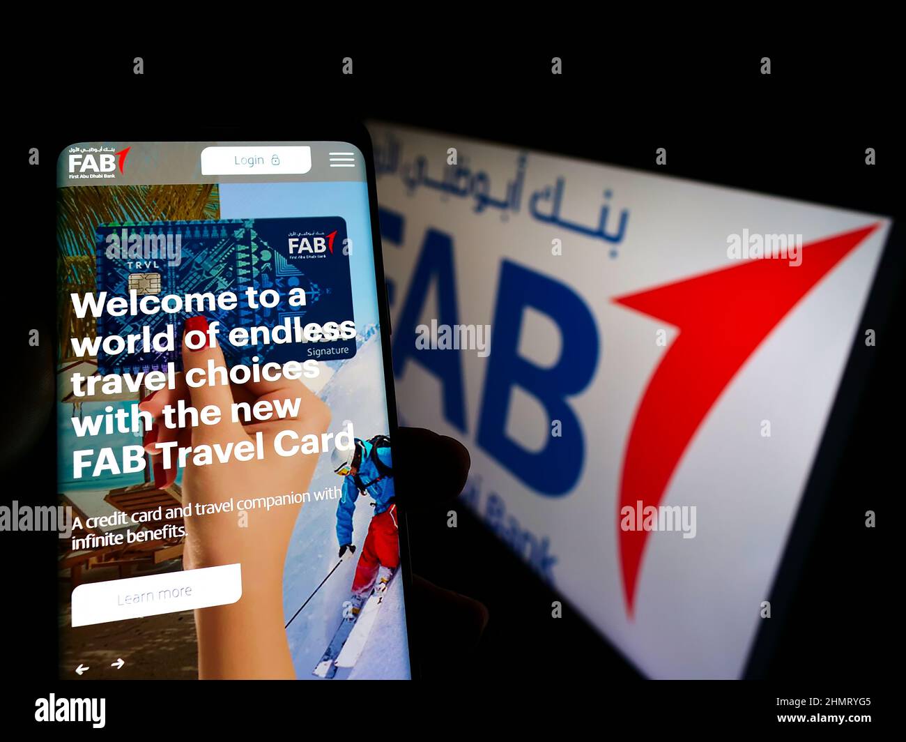 Person holding cellphone with website of financial company First Abu Dhabi Bank (FAB) on screen with logo. Focus on center of phone display. Stock Photo