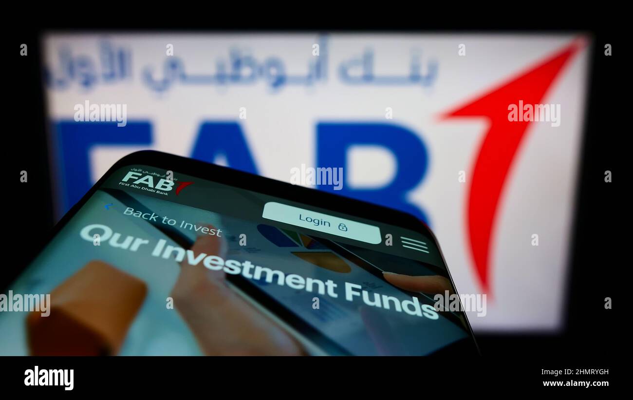 Smartphone with webpage of financial company First Abu Dhabi Bank (FAB) on screen in front of business logo. Focus on top-left of phone display. Stock Photo