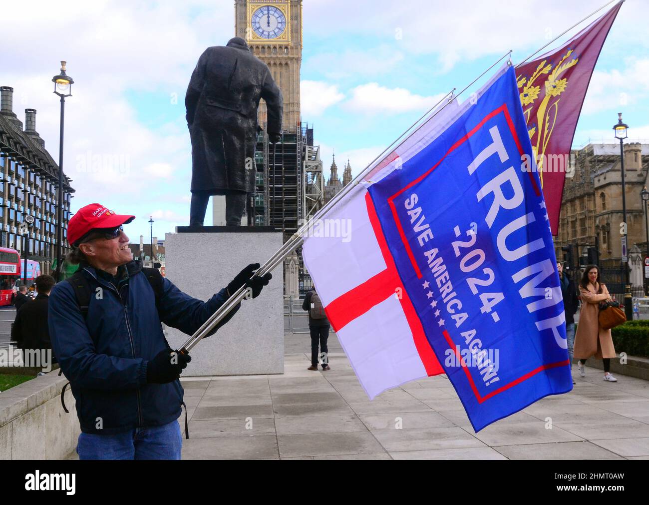 A supporter of Donald Trump holds flags supporting the ex President across the road from the House of Commons, United Kingdom, British Isles. Stock Photo