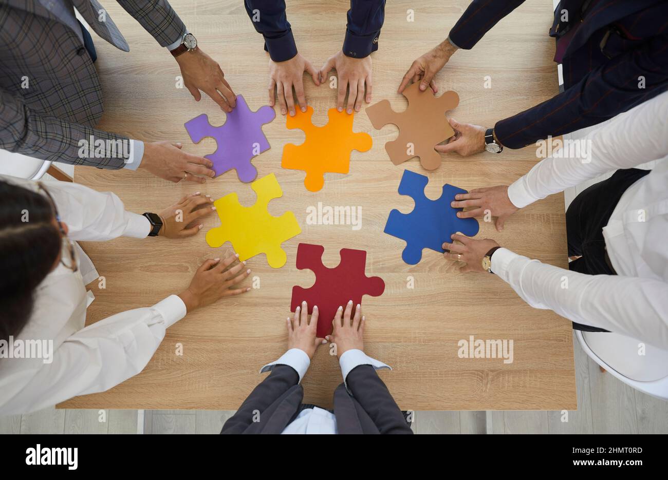 Employees connect jigsaw puzzles involved in teambuilding Stock Photo