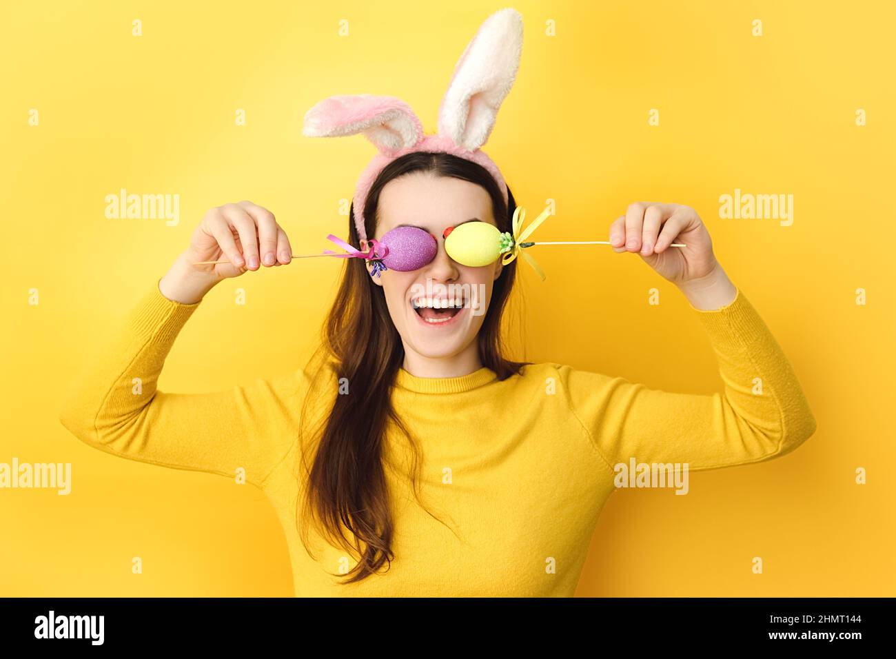 Funny young caucasian woman covers eyes with two Easter eggs, wears ...