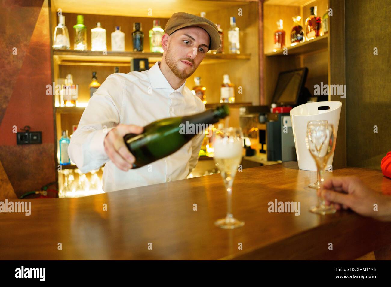 Barman pouring drink in glasses in bar Stock Photo