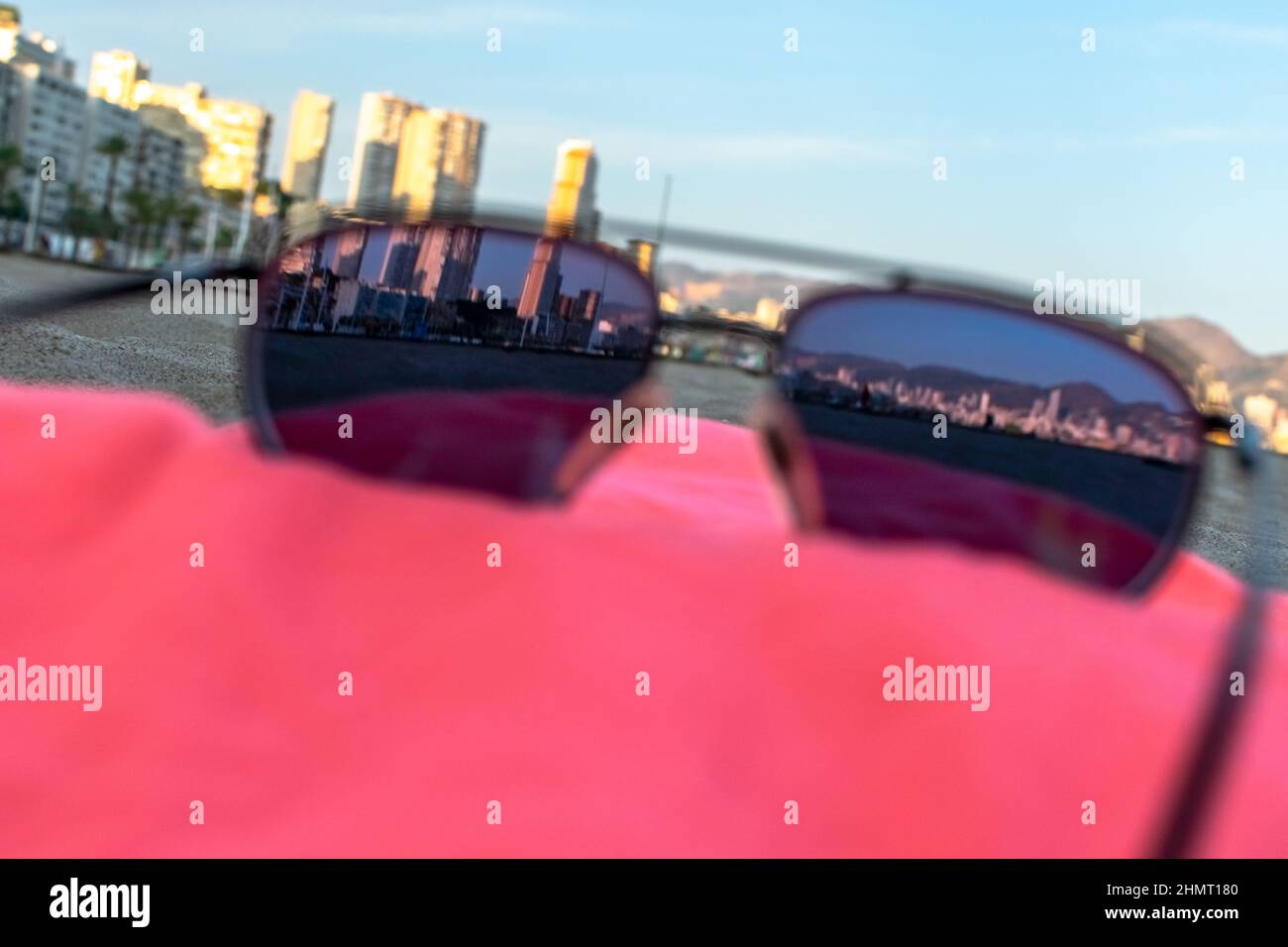 Sunglasses view of Benidorm city in a red towel. In the beach of Poniente, city towers seen throught a tinted sunglasses laid down in a golden hour. Stock Photo