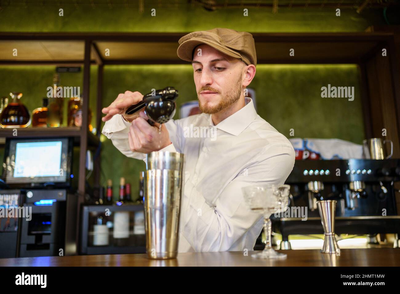 Male barkeeper squeezing lemon into cocktail in a pub Stock Photo