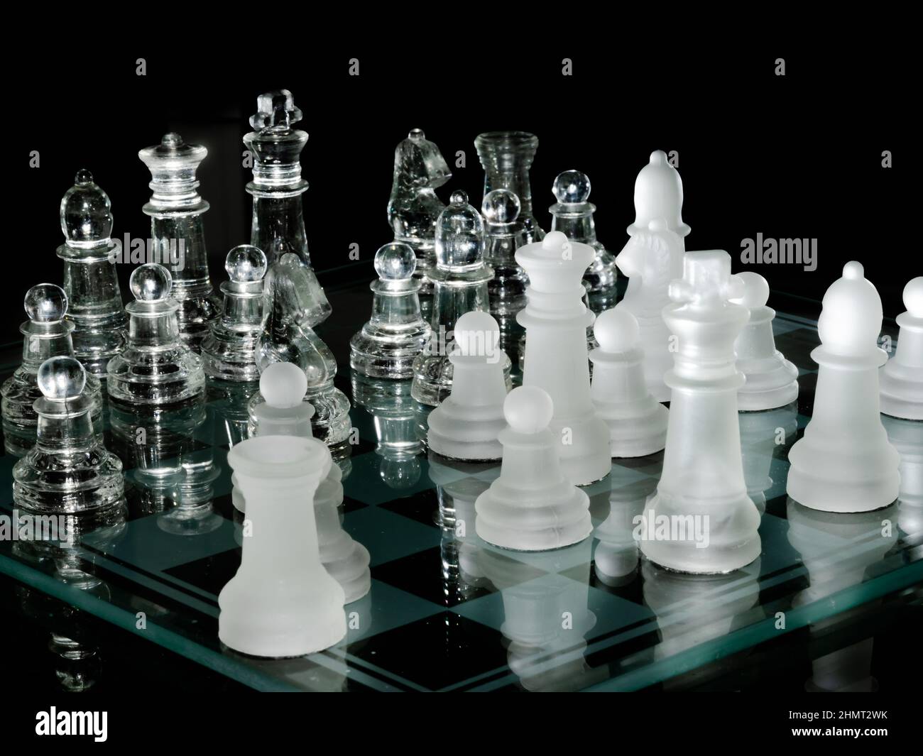 Chess set with glass material reflected. White pieces and transparent resin material reflected in the glass chess board. Black backgroud. Close up. Stock Photo