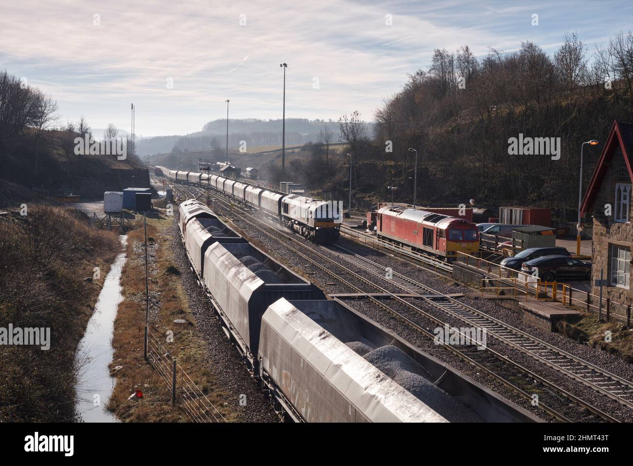 Freight trains at  Peak Forest, Derbyshire with a GB Railfright class 66 locomotive departing with a heavy aggregates train with the sanders working Stock Photo