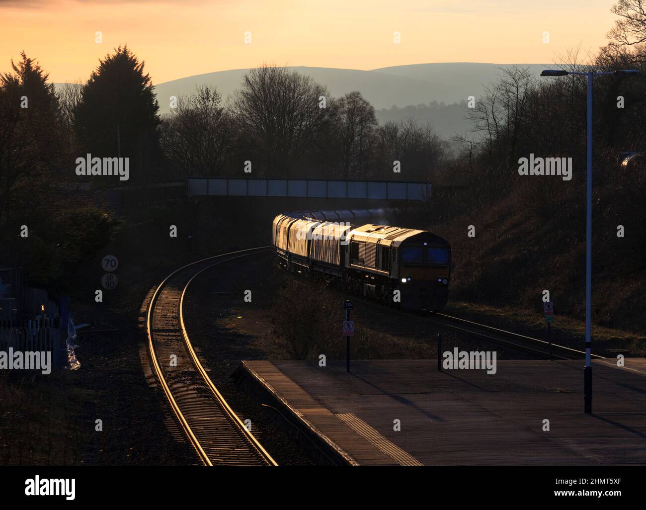 GB railfreight class 66 diesel locomotive passing  Chinley, Hope valley, Derbyshire with a freight train of empty wagons at sunset Stock Photo