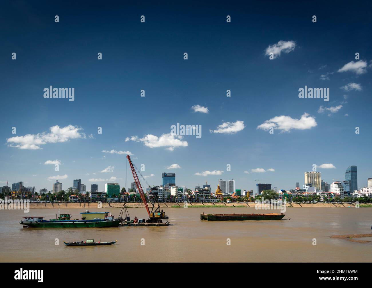sand dredging boats on the Tonle Sap river with Phnom Penh city skyline in Cambodia Stock Photo