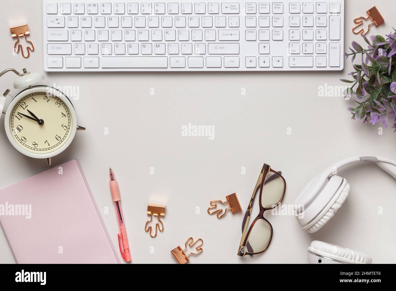 Desktop. Notepad keyboard alarm clock glasses headphones on the table. Frame with copy space Stock Photo