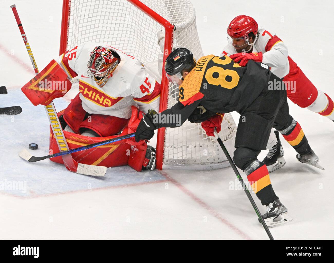Beijing, China. 12th Feb, 2022. Olympics, ice hockey, preliminary round, Group A, Germany - China, at the National Indoor Stadium, David Wolf of Germany (M) gets a shot off against goalkeeper Jieruimi Shimisi (Jeremy Smith) and Jieke Kailiaosi (Jake Chelios) of China. Credit: Peter Kneffel/dpa/Alamy Live News Stock Photo