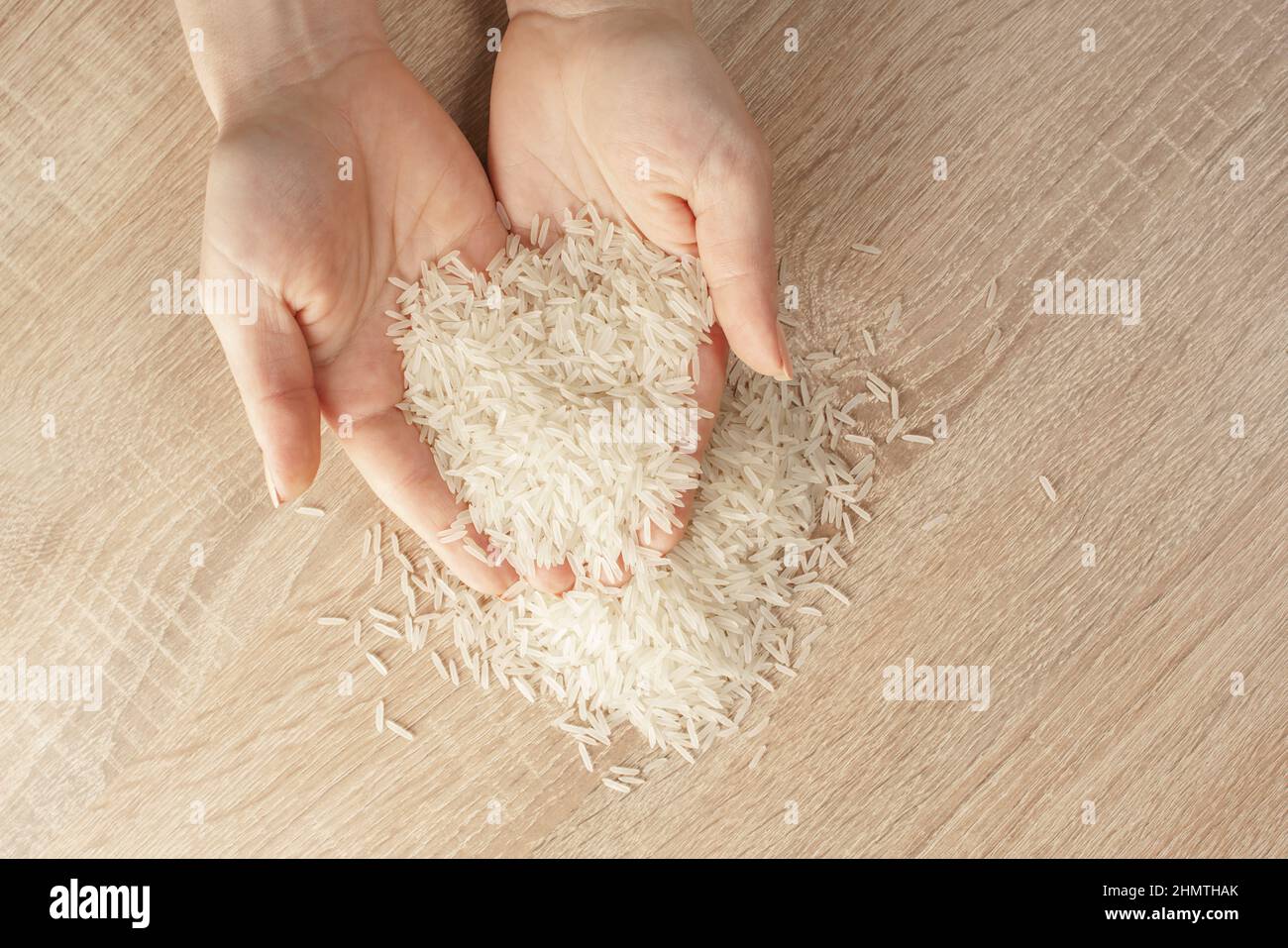 raw rice in hands on wooden background Stock Photo