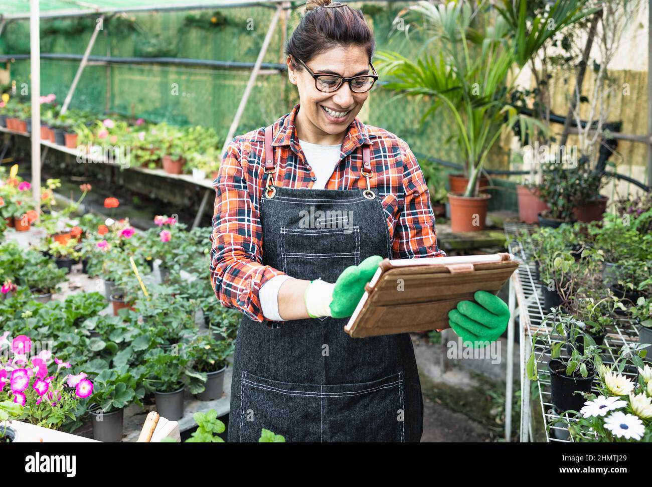 Hispanic woman working with digital tablet in flower garden shop Stock Photo