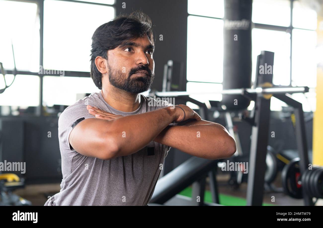 medium close up shot Young Indian athelete doing squats excerise at gym - concept of healthy lifestyle, fitness and bodybuilding. Stock Photo