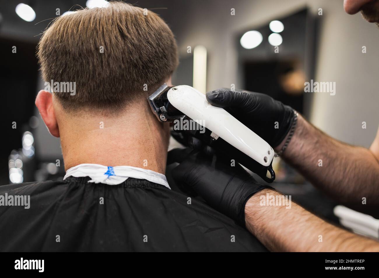 Barber cutting a man's hair with a clipper. Haircut process in salon