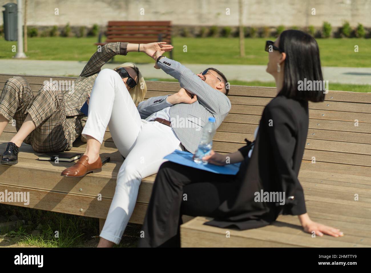 Three urban business people are sitting on the bench while they are on
