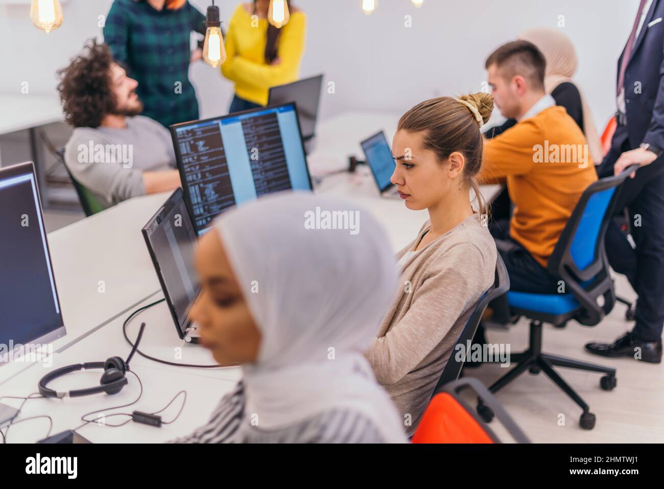 Group of multi-ethnic colleagues working on desktop computers in a ...