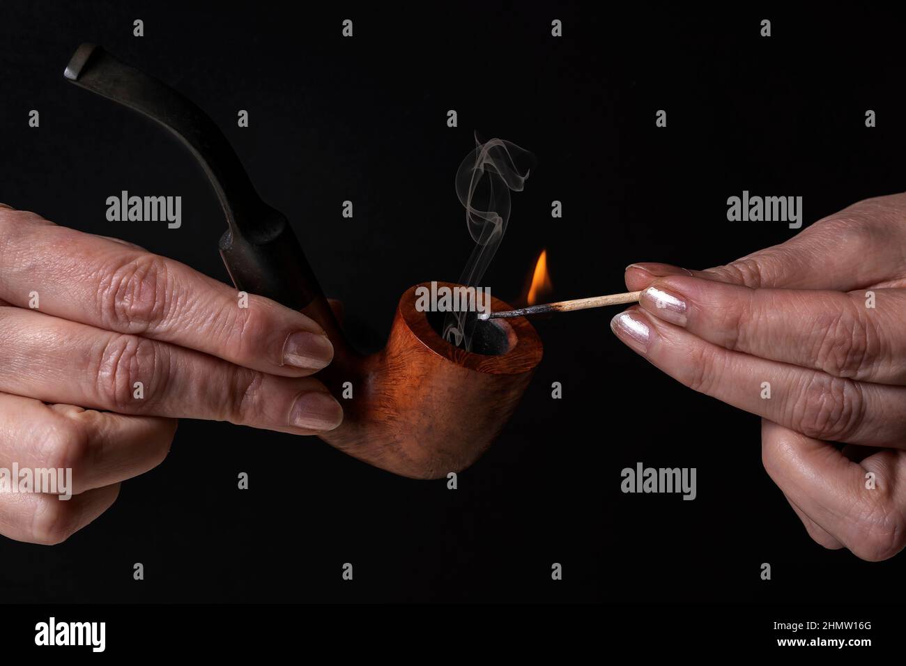Female hands light a wooden pipe with a lit match Stock Photo - Alamy