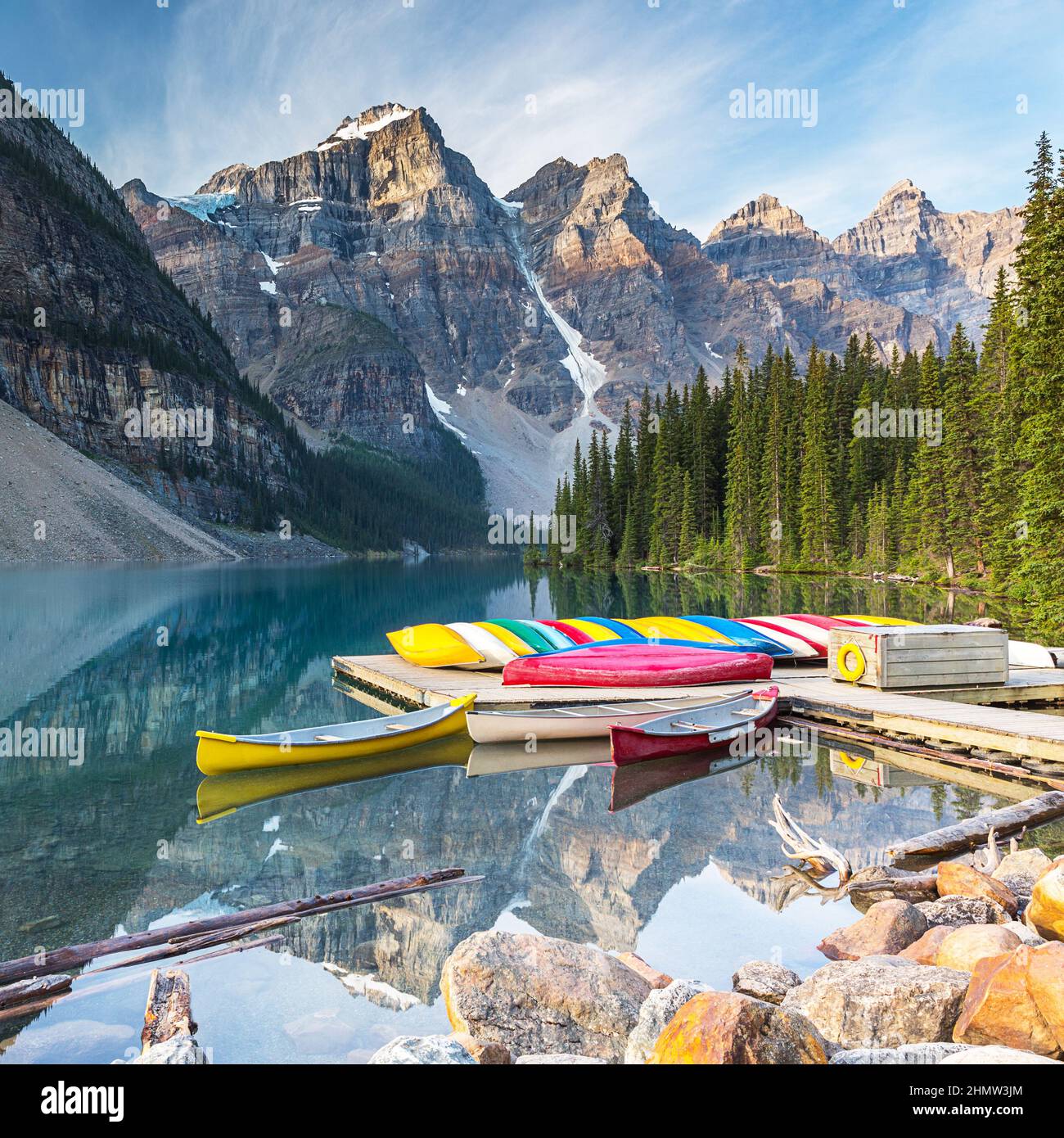Canoes on a jetty at  Moraine lake in Banff National Park, Alberta, Canada, with snow-covered peaks of canadian Rocky Mountains in the background Stock Photo