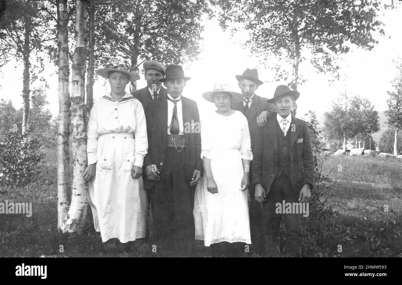 Early 20th century authentic vintage photograph of four men and two women in hats posing in rural landscape, Sweden Stock Photo