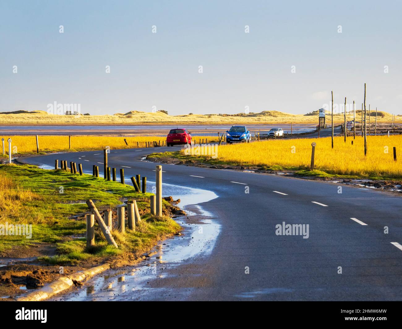 Cars crossing the causeway at low tide to Holy Island, Northumberland, UK. Stock Photo