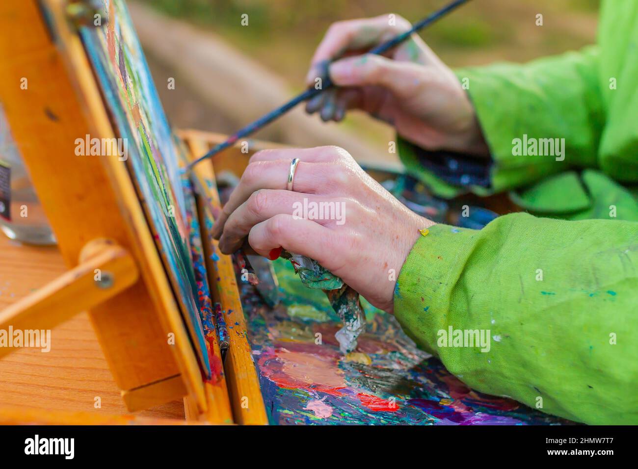 Closeup of an artist picking up a brush with paint on the color palette