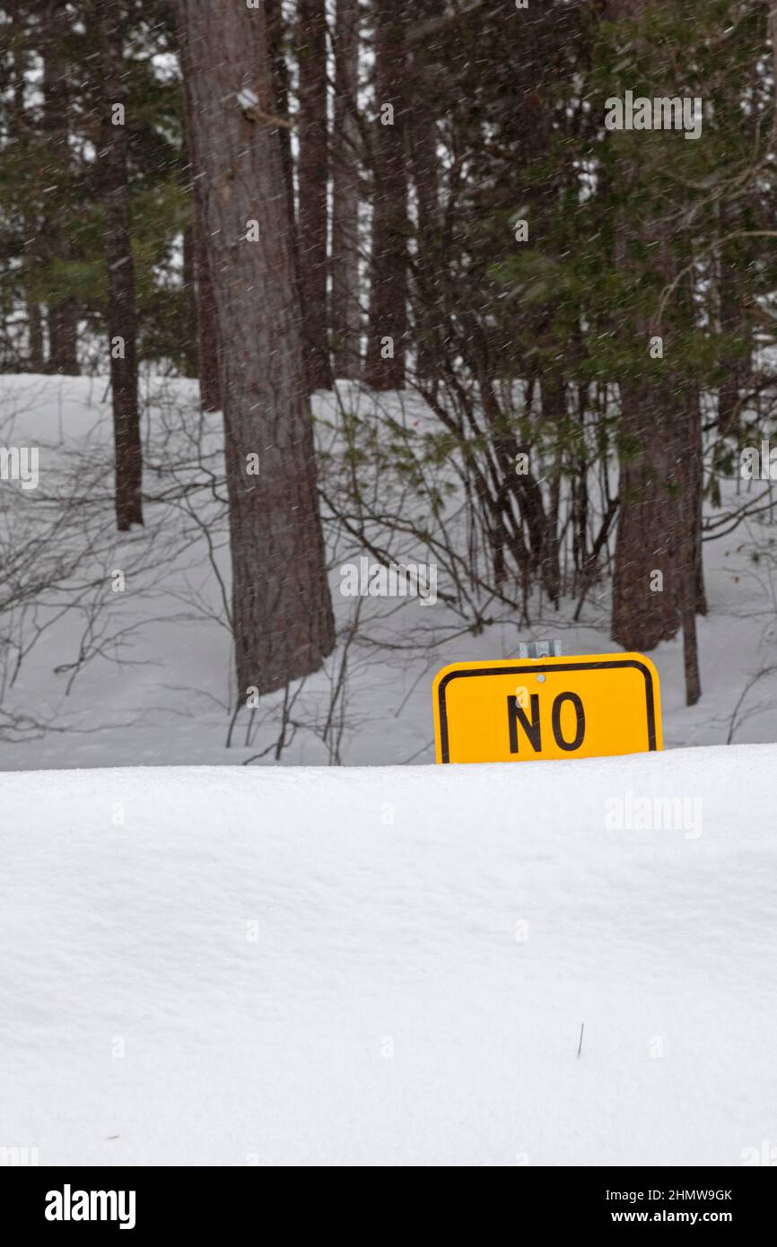 Seney, Michigan - A sign prohibiting something at a highway rest area in Michigan's upper peninsula is partially obscured by piles of snow. Stock Photo