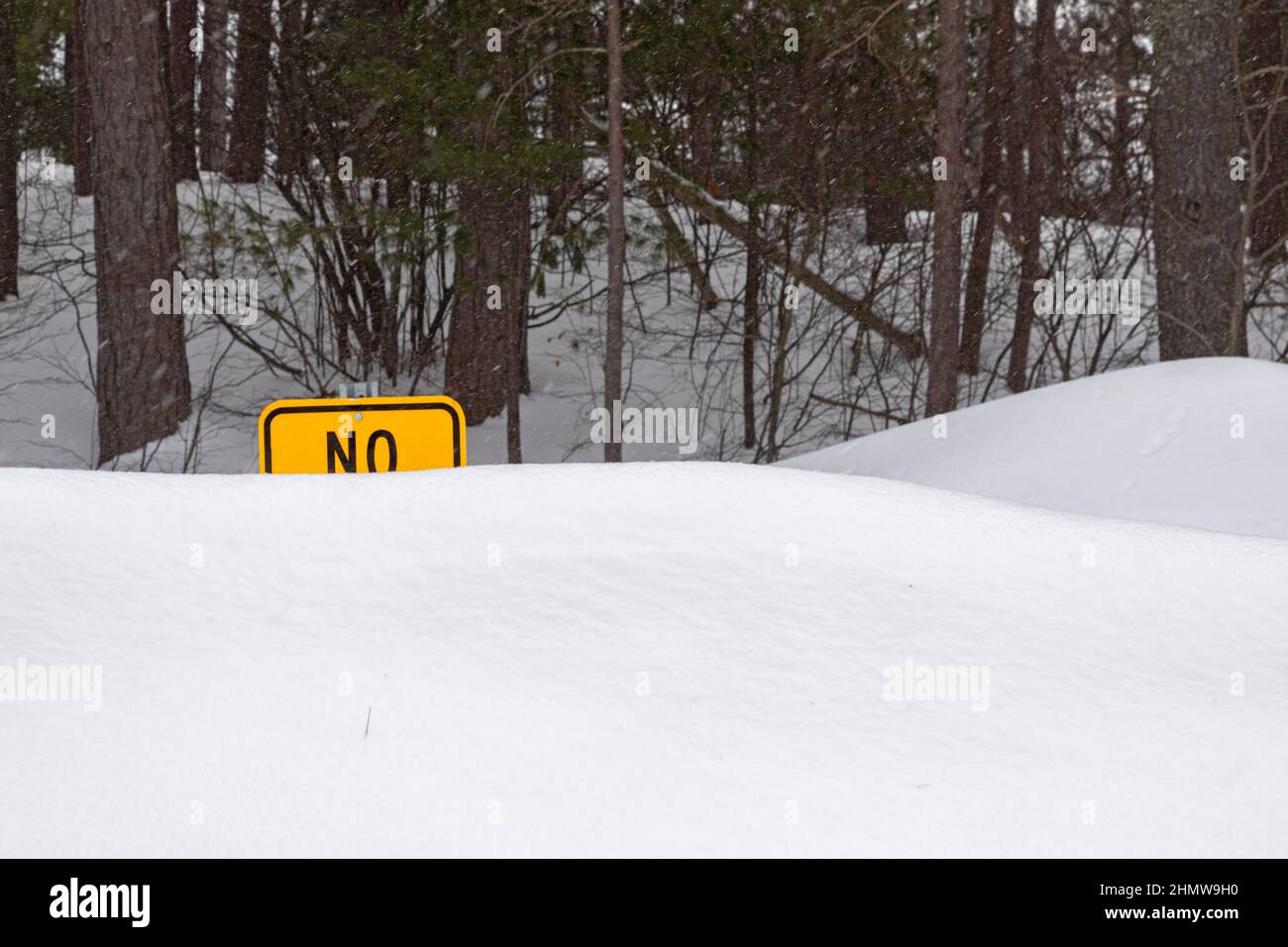 Seney, Michigan - A sign prohibiting something at a highway rest area is partially obscured by piles of snow in Michigan's upper peninsula. Stock Photo
