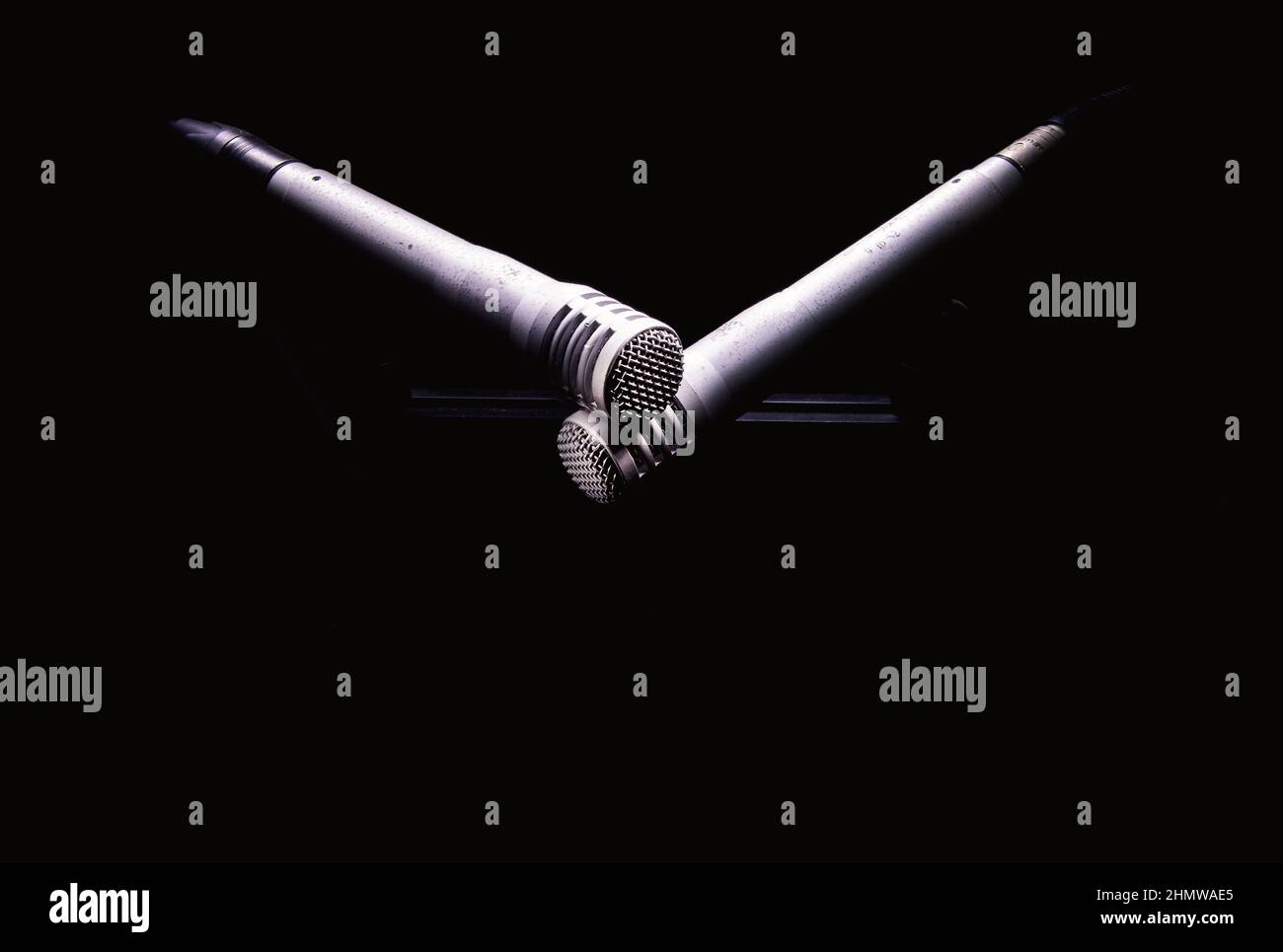 Closeup view of studio microphones on stand in dark, highlighted shapes, XY stereo recording. Stock Photo