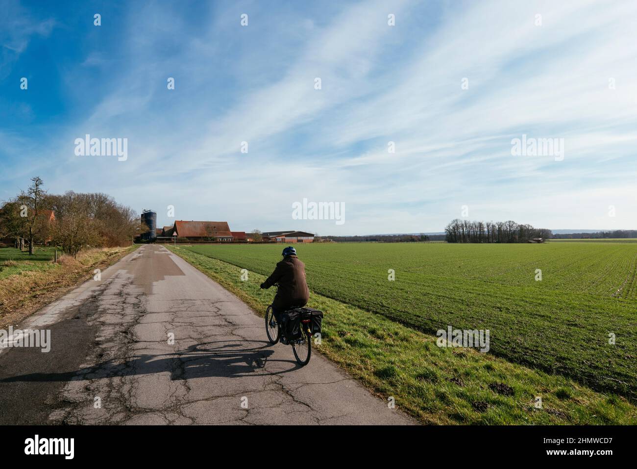 Woman on an electric bicycle on a rural road near Petershagen. Stock Photo