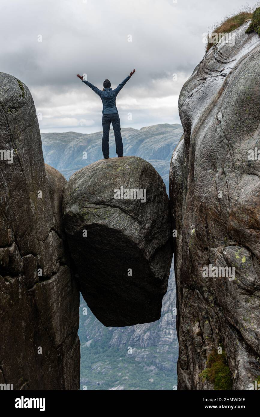 Victory pose on top of Kjeragbolten - boulder wedged in the mountain's crevasse 984 meter above the sea Stock Photo