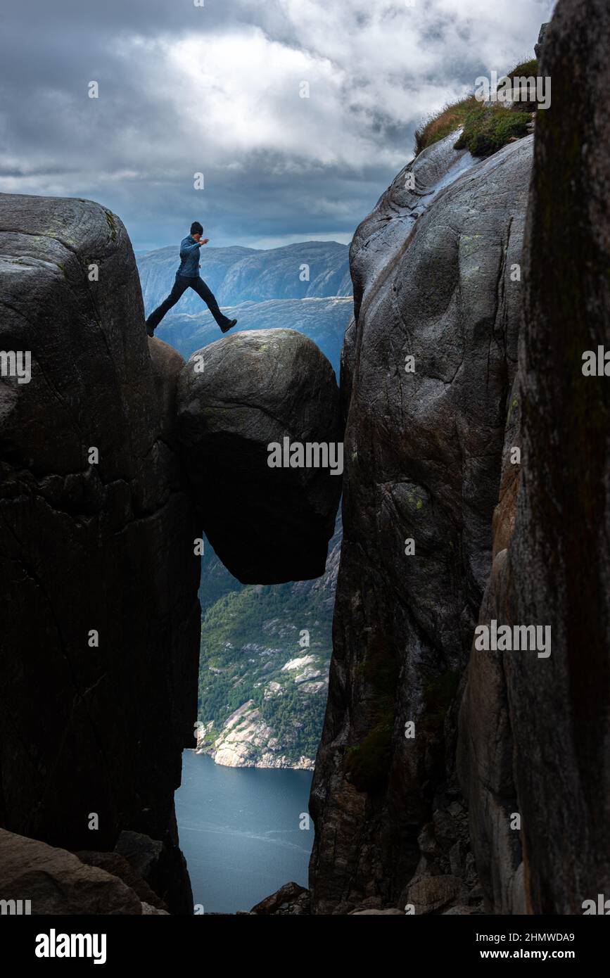Young woman on top of Kjeragbolten - boulder wedged in the mountain's crevasse 984 meter above the sea Stock Photo