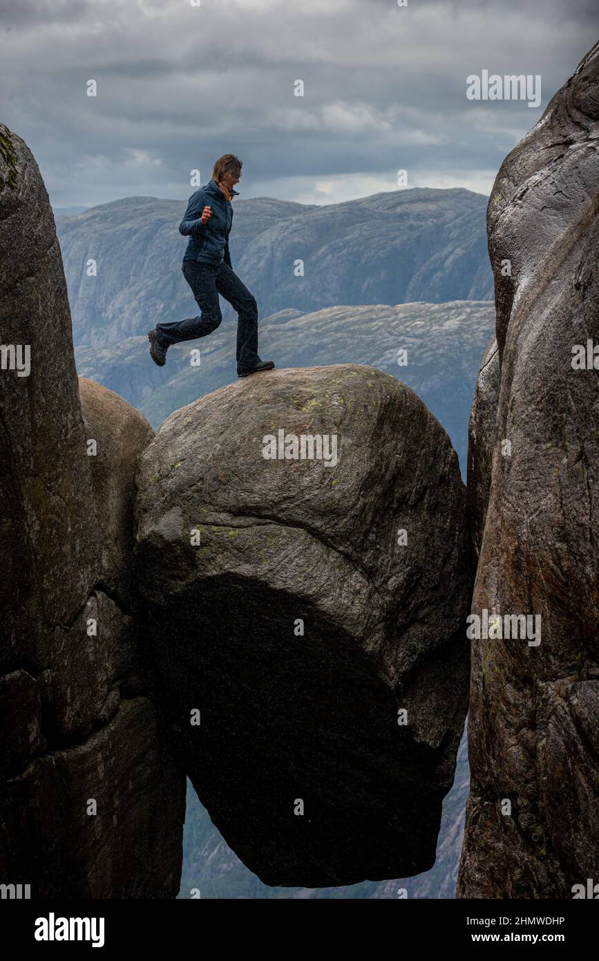 Jumping on top fo Kjeragbolten - boulder wedged in the mountain's crevasse 984 meter above the sea Stock Photo