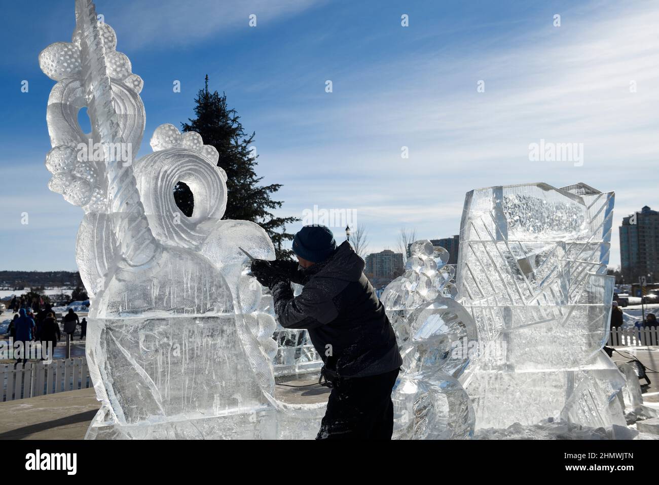 Man working on carving an ice sculpture of a narwhale at Meridian Place in Barrie on Kempenfelt Bay at Winterfest 2022 called Hello Winter Stock Photo