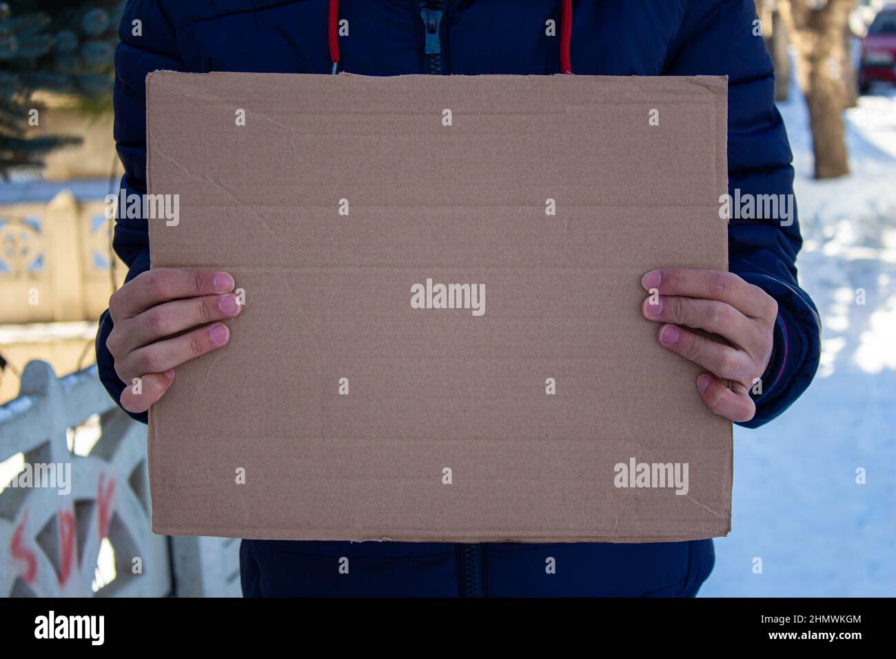 Man holding blank cardboard box, protesting something. Copy space for text on cardboard box. Stock Photo