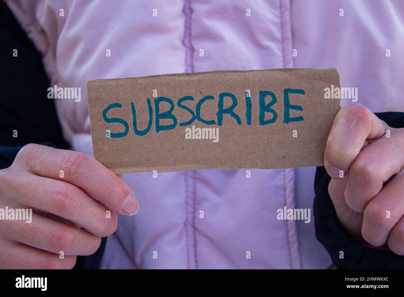 Woman holding cardboard box with subscribe word. Stock Photo