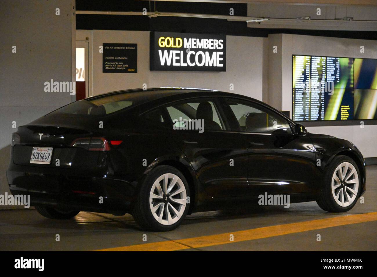 Tesla Model 3 cars sit on in a Hertz rental car parking garage on