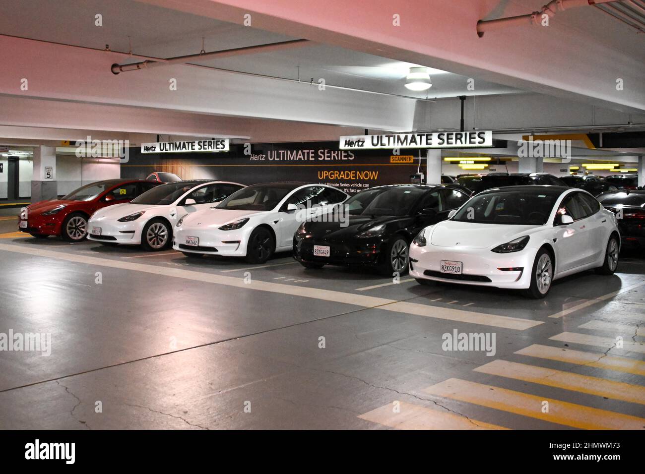 Tesla Model 3 cars sit on in a Hertz rental car parking garage on