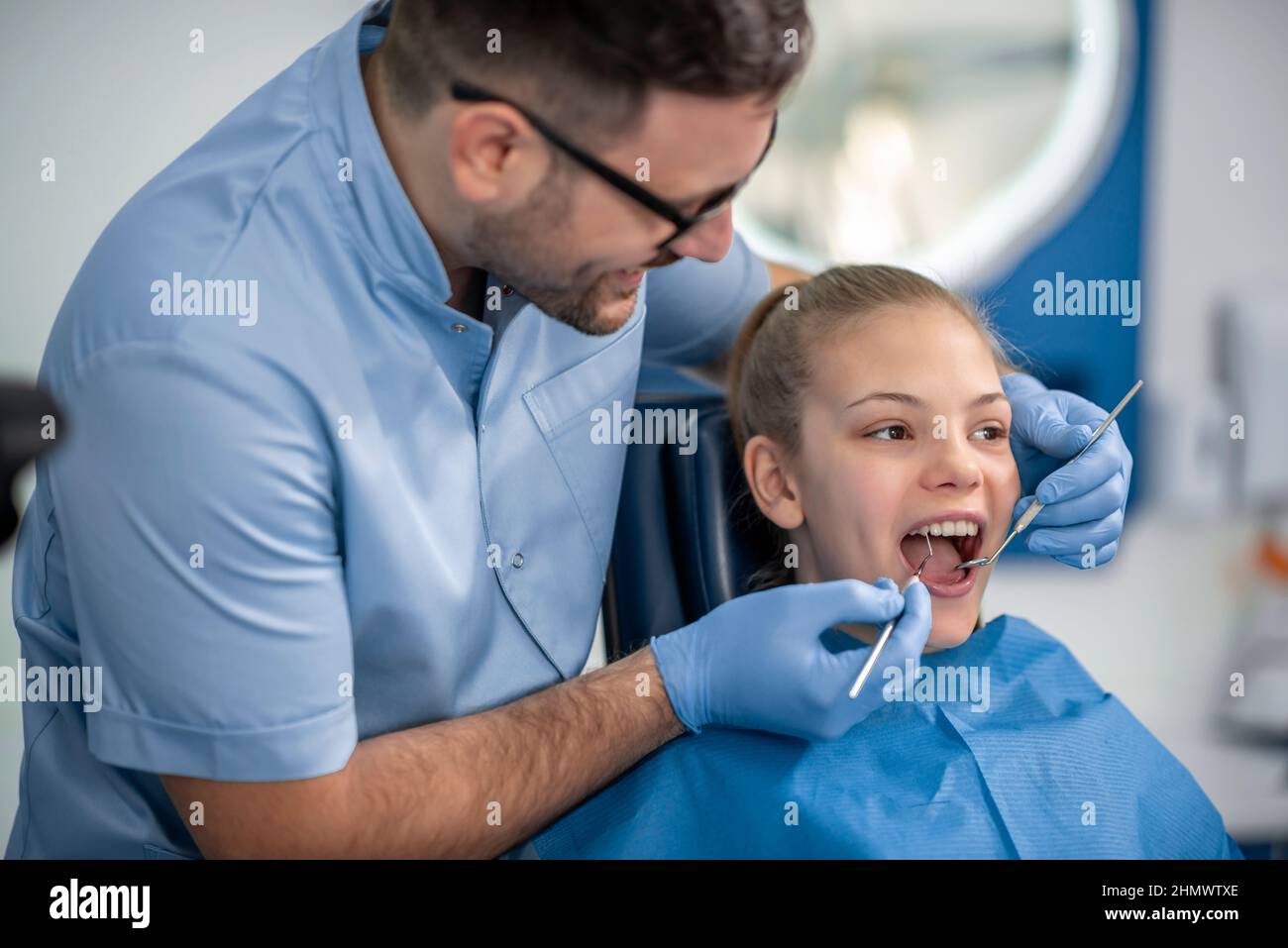 Girl Sitting On Dental Chair And Having Dental Treatment Stock Photo girl-sitting-on-dental-chair-and-having-dental-treatment-stock-photo