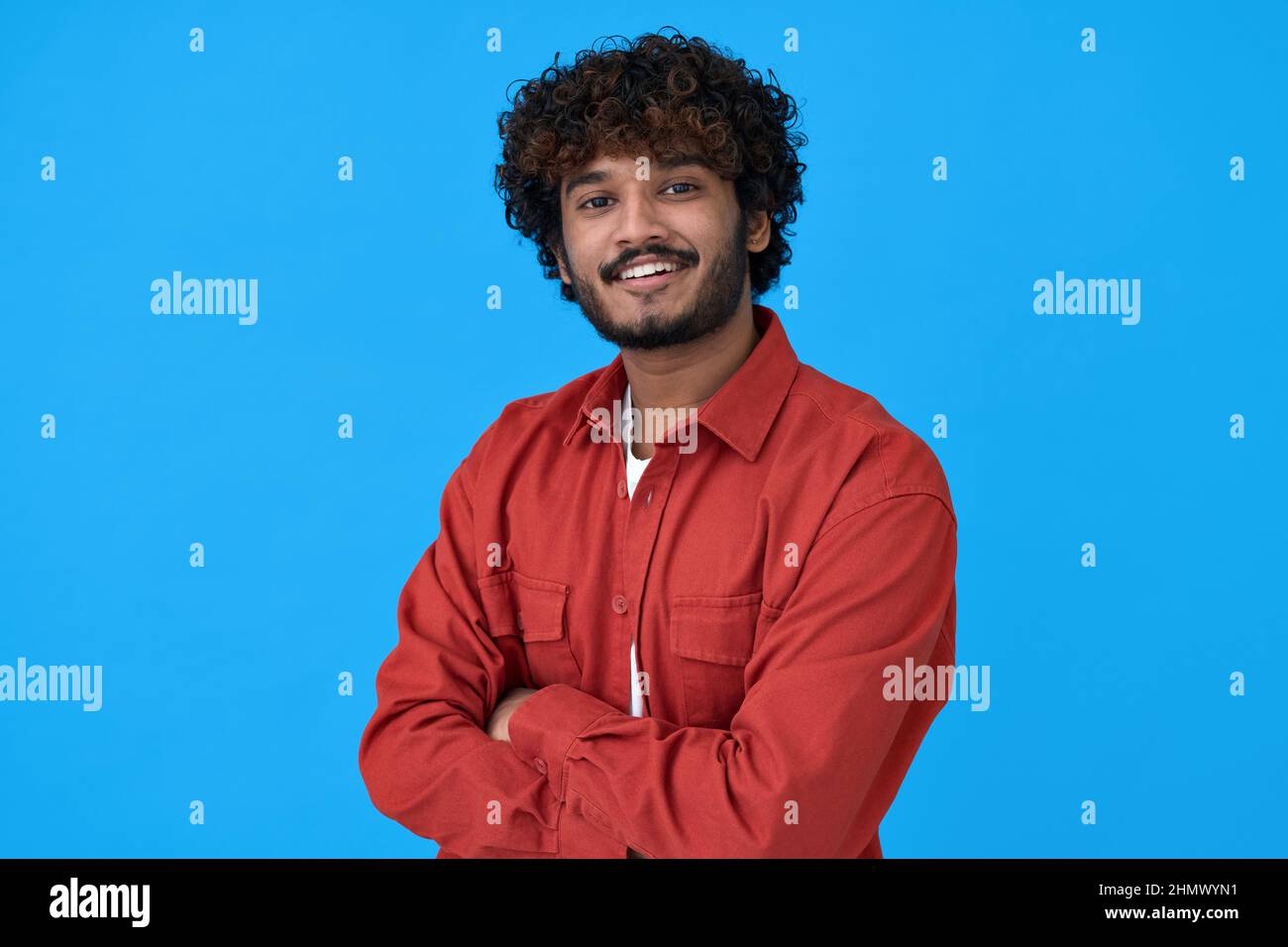 Smiling young indian guy standing isolated on blue background. Stock Photo