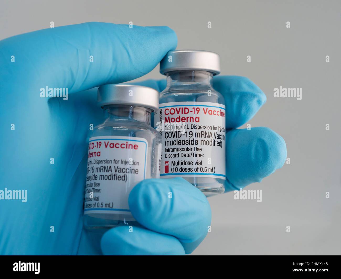 Close-up a vial with Moderna Covid-19 vaccine, held by a hand in medical gloves Stock Photo