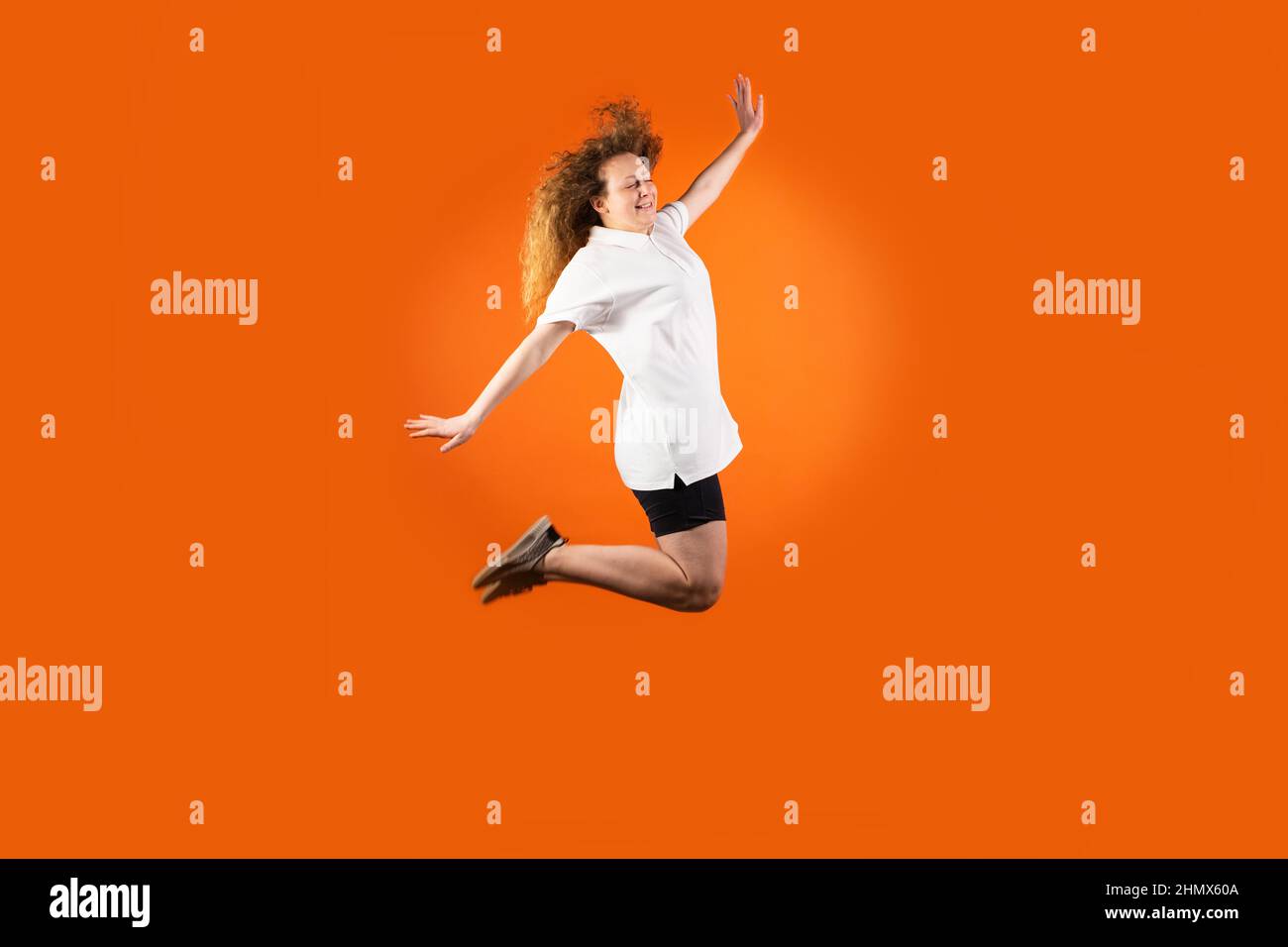 The young redhead woman in football uniform isolated jumping very high as a flight to the sun, fan human emotions concept. Stock Photo