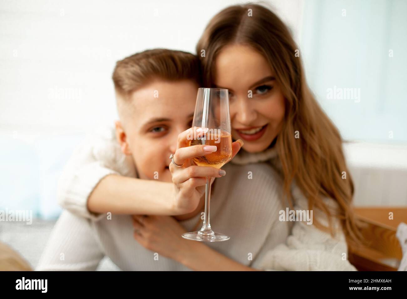 Glass glass with wine in hands of charming happy brown-haired woman who hugs her beloved. Love at first sight. Romantic relationships.A love story Stock Photo