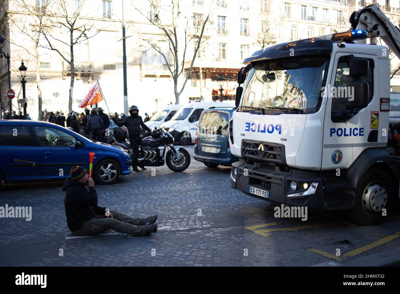 Protester next to a Police truck on the Champs Elysees in Paris near the Arc de Triomphe on February 12, 2022 as convoys of protesters so called Convoi de la Liberte arrived in the French capital. Thousands of protesters in convoys, inspired by Canadian truckers paralysing border traffic with the US, were heading to Paris from across France on February 11, with some hoping to blockade the capital in opposition to Covid-19 restrictions despite police warnings to back off. The protesters include many anti-Covid vaccination activists, but also people protesting against fast-rising energy prices t Stock Photo