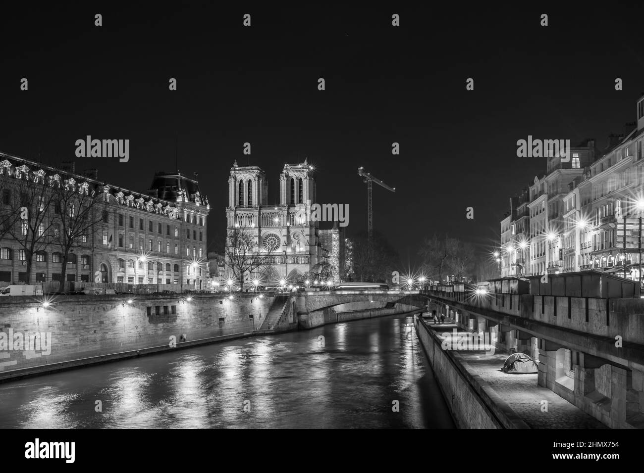 Paris, France - February 11, 2022 : The  illuminated famous cathedral of Notre Dame and the seine river in Paris France by night in black and white Stock Photo