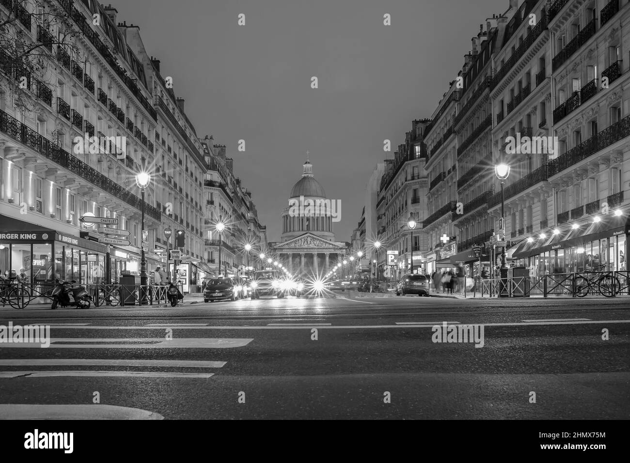 Paris, France - February 11, 2022 : Busy traffic at a boulevard in Paris and the famous Pantheon monument in the background at night Stock Photo