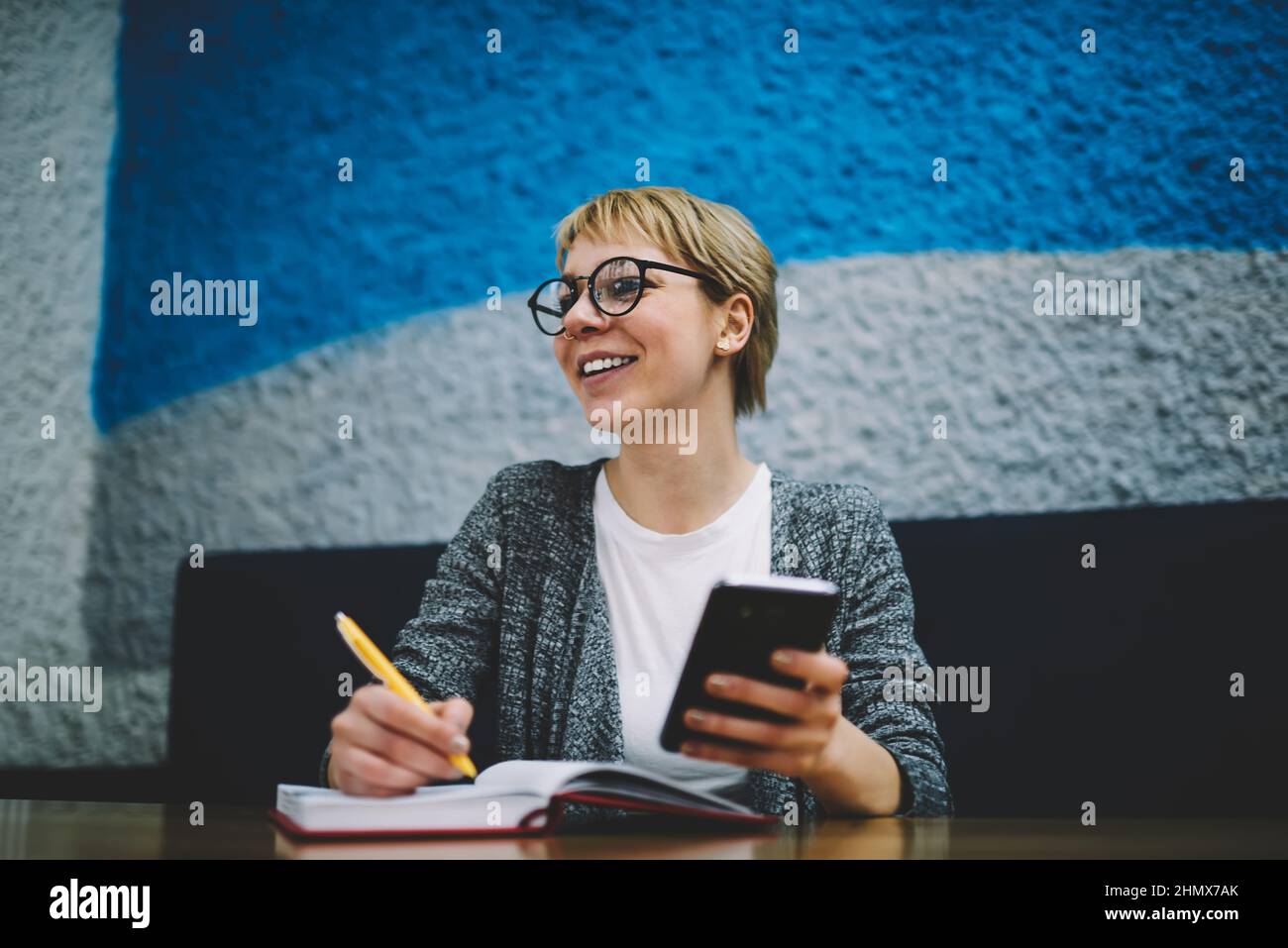 Happy woman with smartphone and notepad Stock Photo